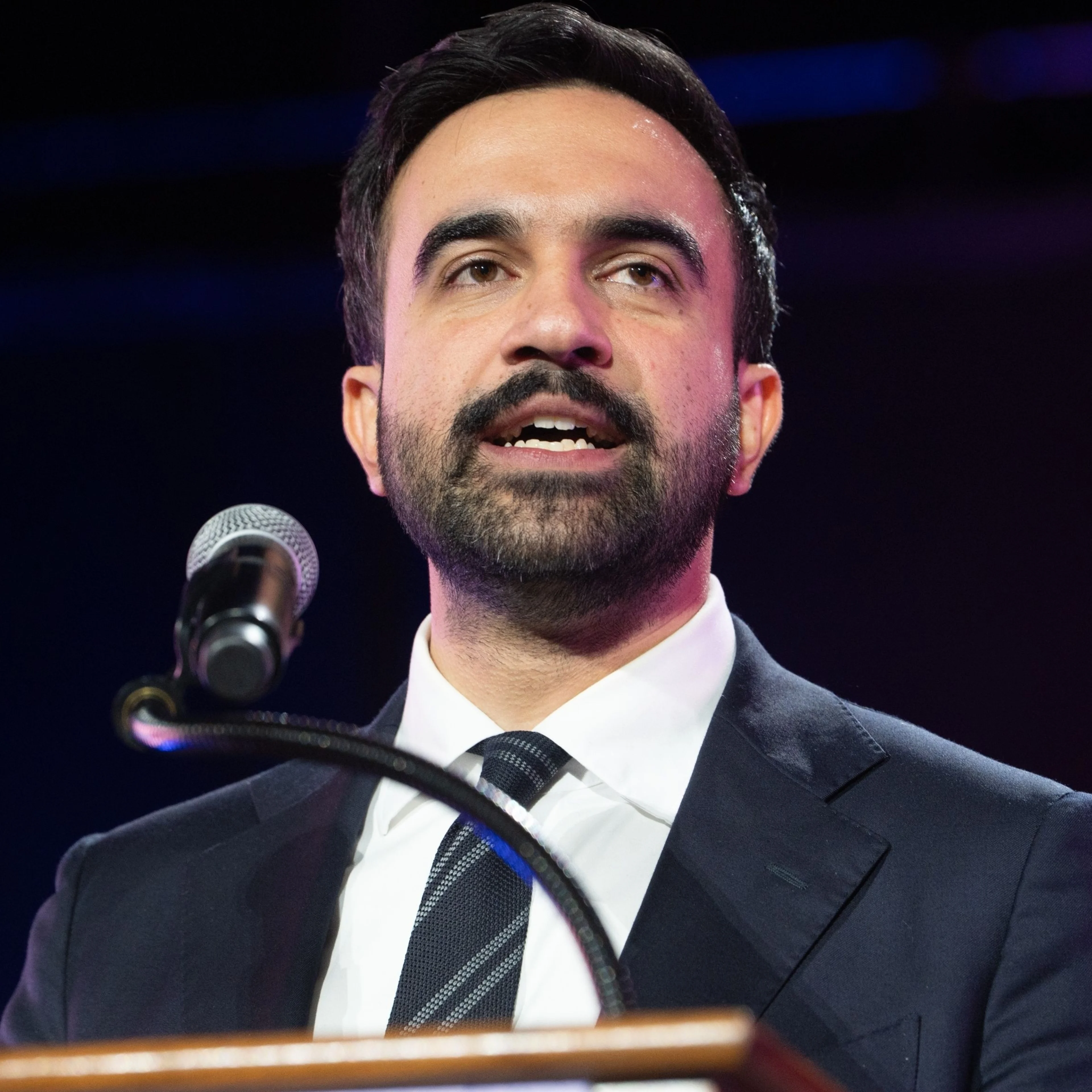 A close up shot of a man speaking behind a podium