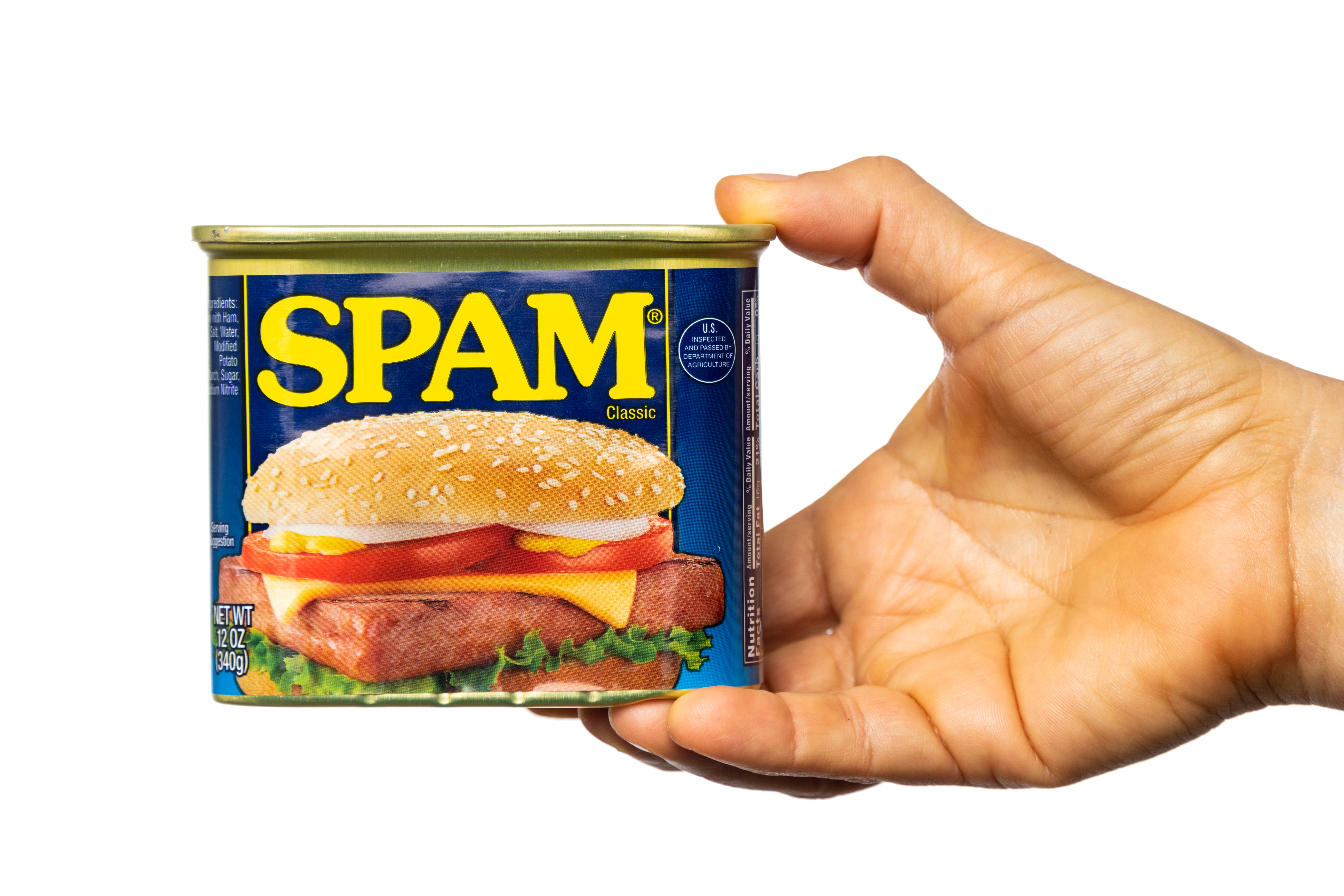 A hand holding a blue 12 oz can of SPAM Classic with yellow lettering, featuring a sandwich image on the label.