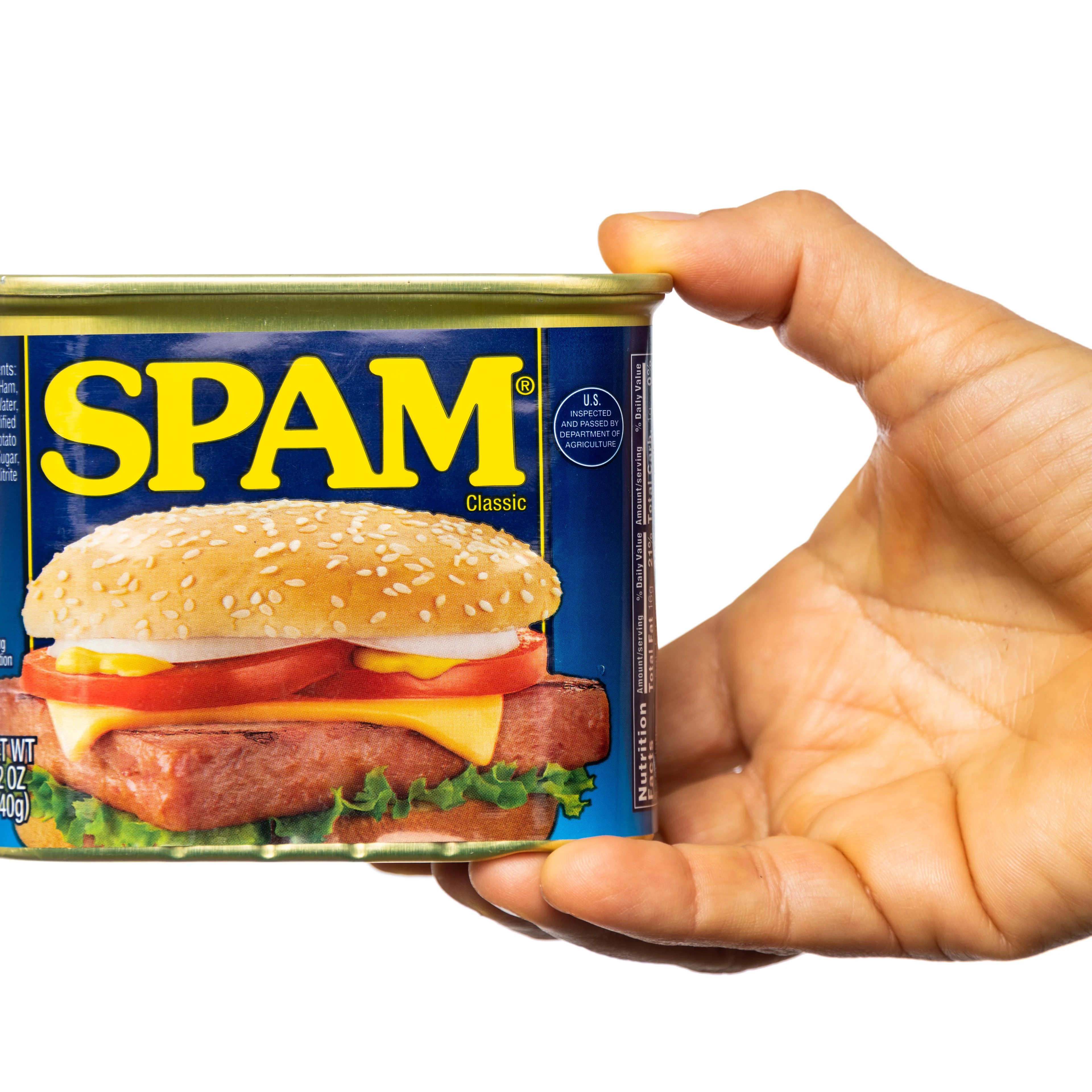 A hand holding a blue 12 oz can of SPAM Classic with yellow lettering, featuring a sandwich image on the label.
