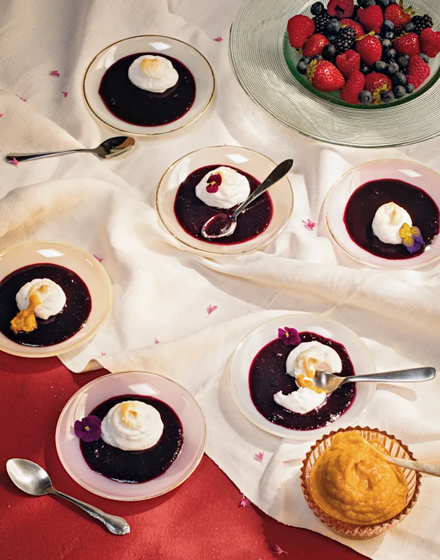 Berry desserts with whipped cream in small dishes, alongside fresh berries in a glass bowl and a small tart.