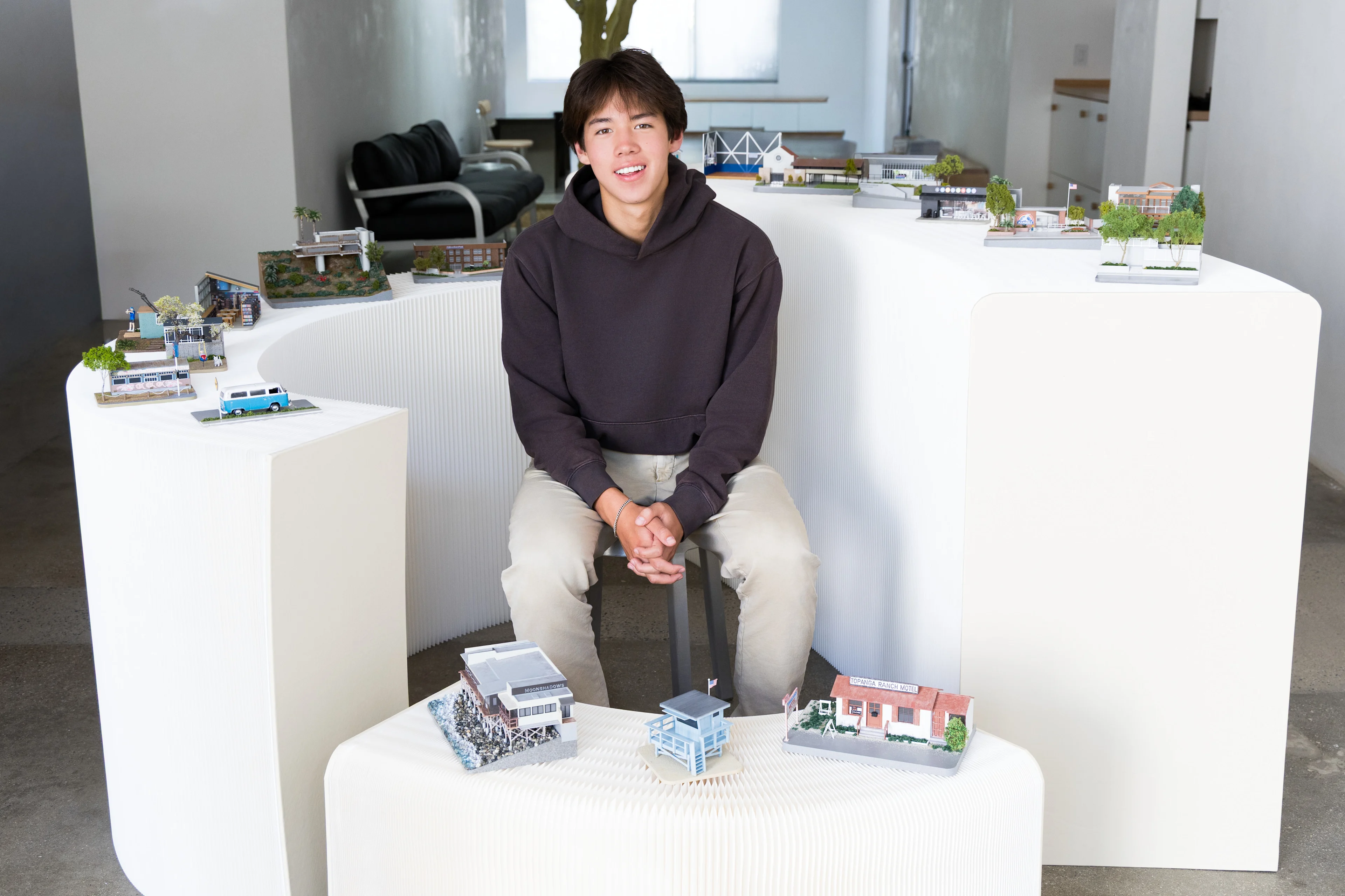 A teenager sits in the middle of dozens of miniature recreations of homes and businesses.