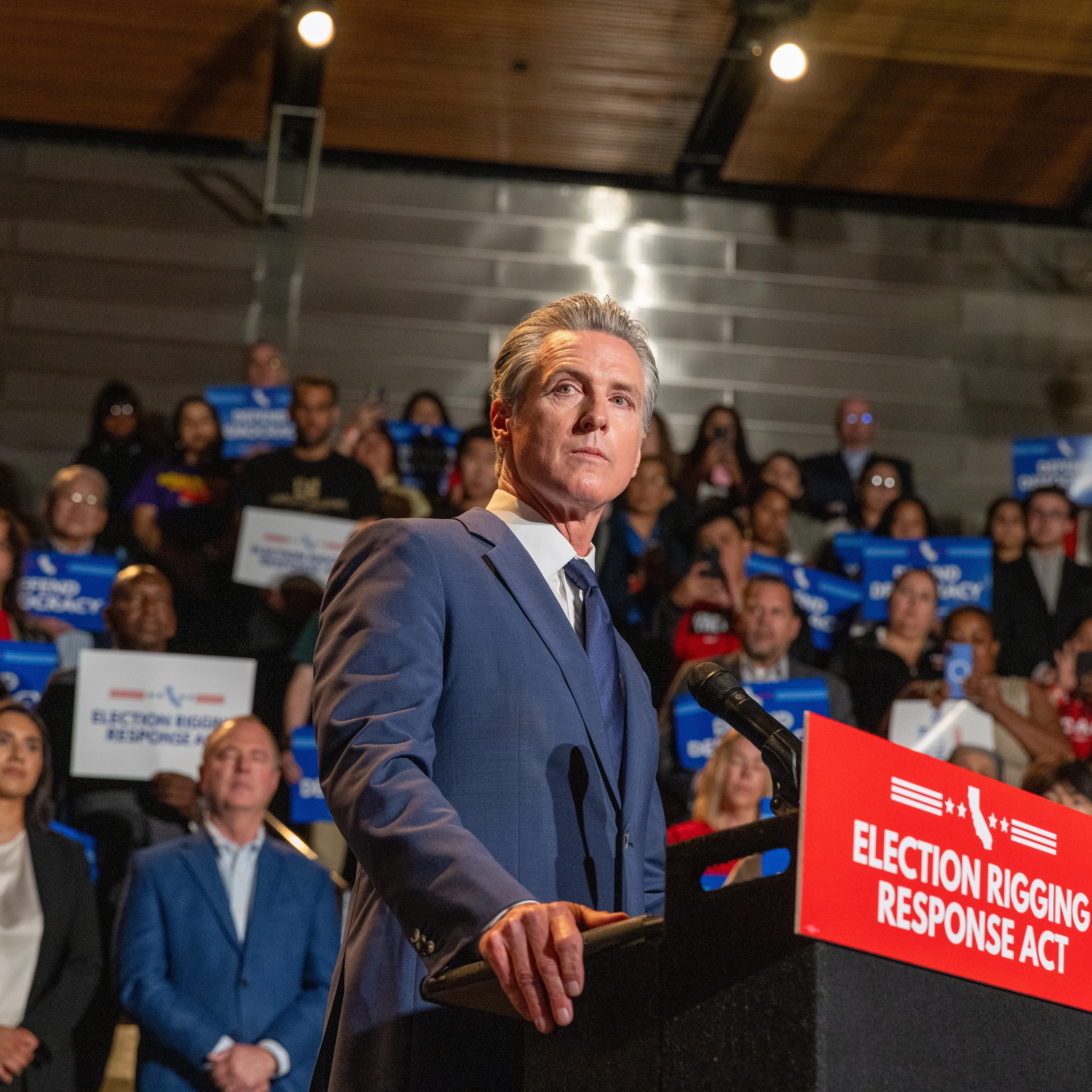 Governor Gavin Newsom stands at a podium with supports behind him to announce his plan to hold a special election.