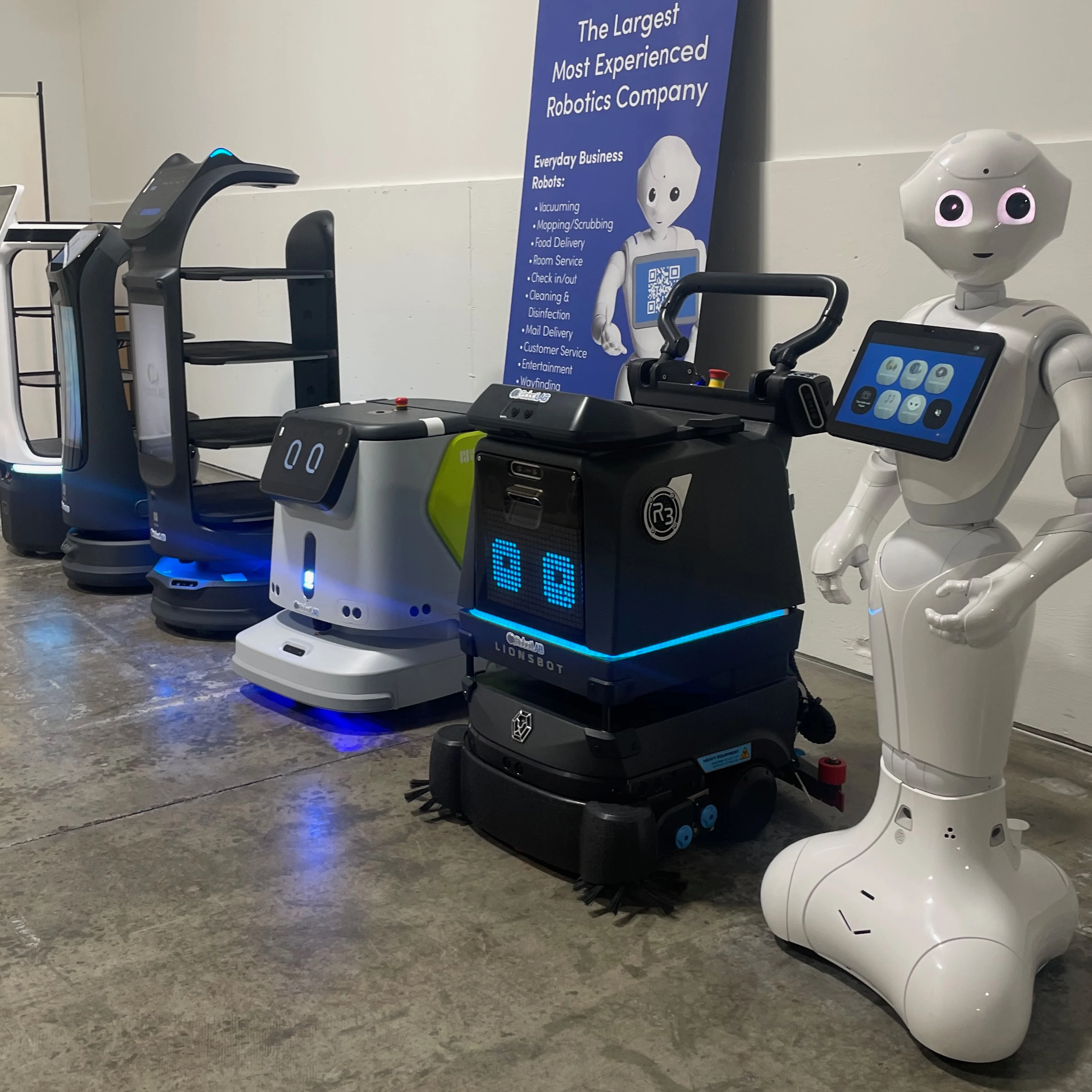 Six models of different types of service robots lined up against a wall.