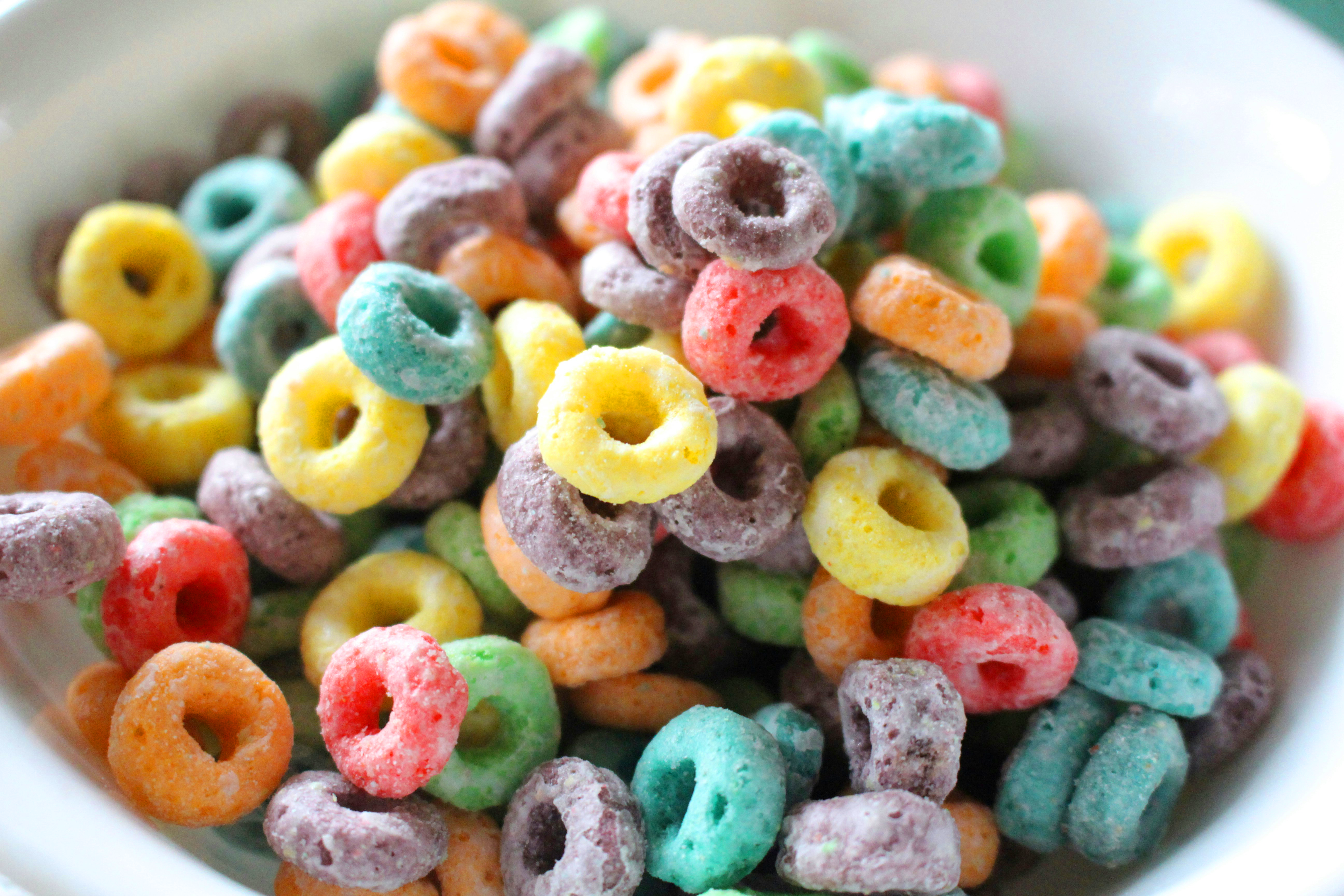 A white bowl filled with colorful fruit-flavored cereal loops in red, yellow, green, orange, teal, and purple hues.