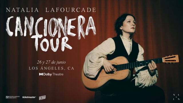 Musician performing with acoustic guitar against red curtain backdrop for Cancionera Tour at Dolby Theatre, Los Angeles.
