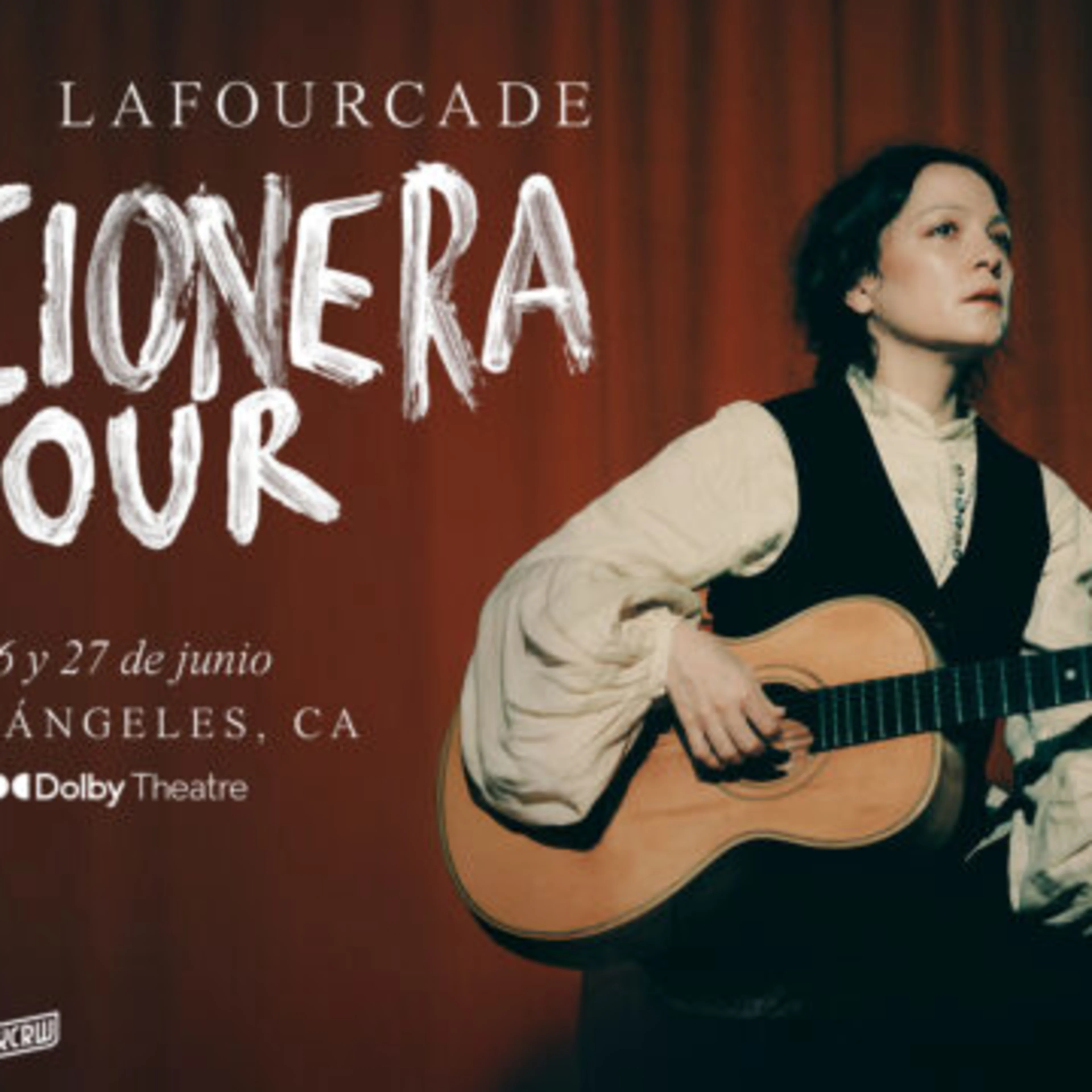 Musician performing with acoustic guitar against red curtain backdrop for Cancionera Tour at Dolby Theatre, Los Angeles.