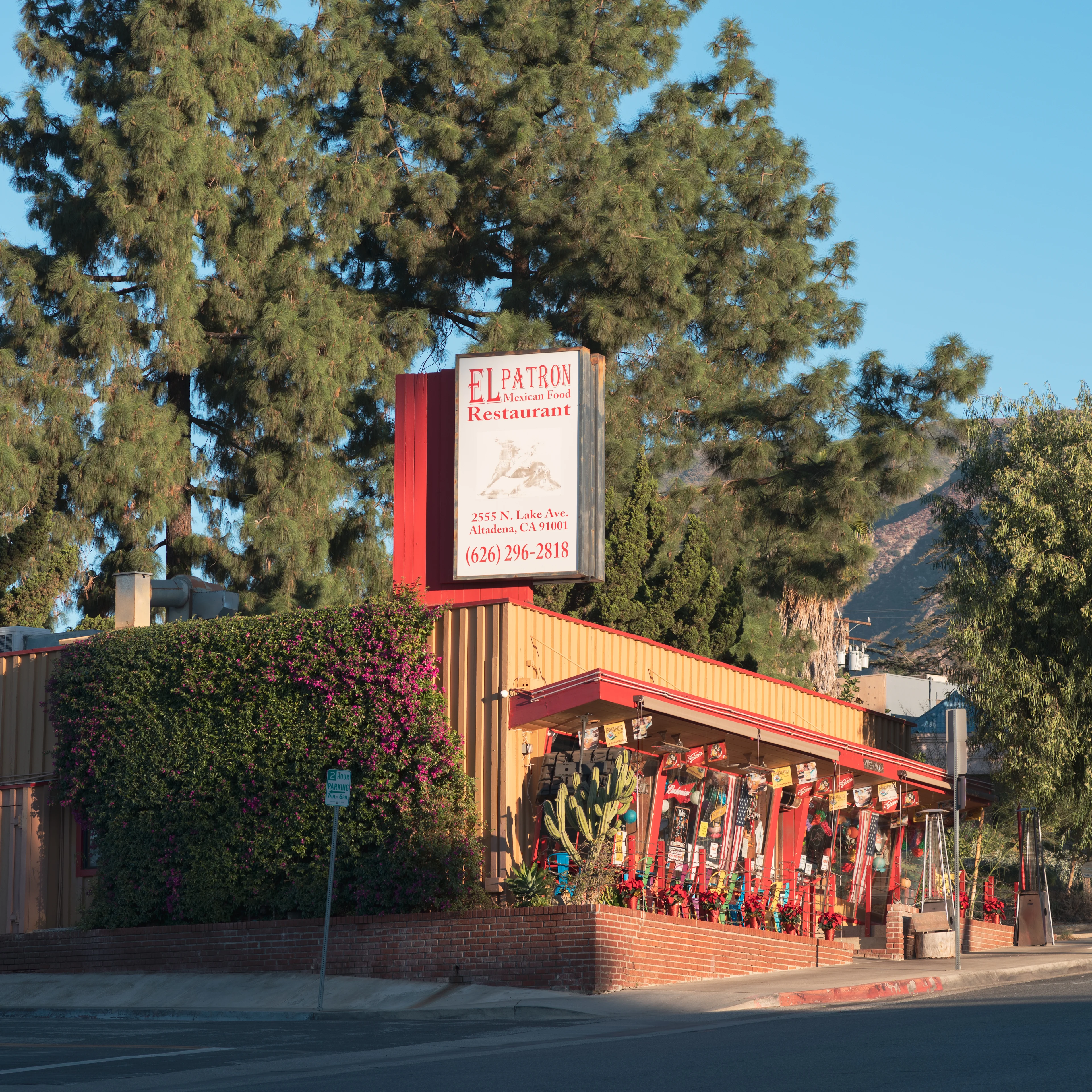 El Patron Mexican restaurant with red trim exterior, surrounded by pine trees and mountains, with American flag nearby.