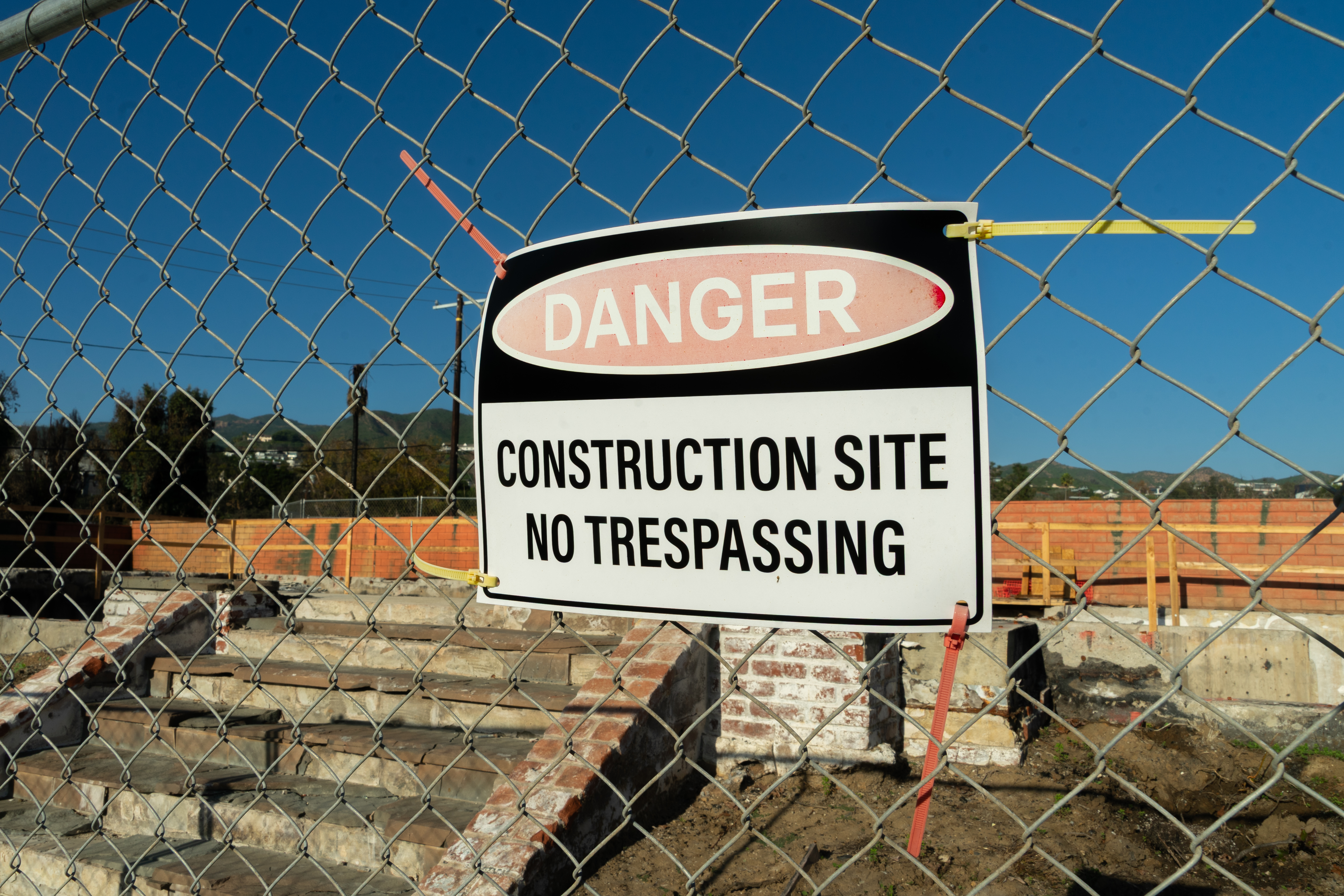 A sign that reads 'Danger: Construction Site, No Trespassing' in the Pacific Palisades one year after the Palisades Fire destroyed thousands of buildings.