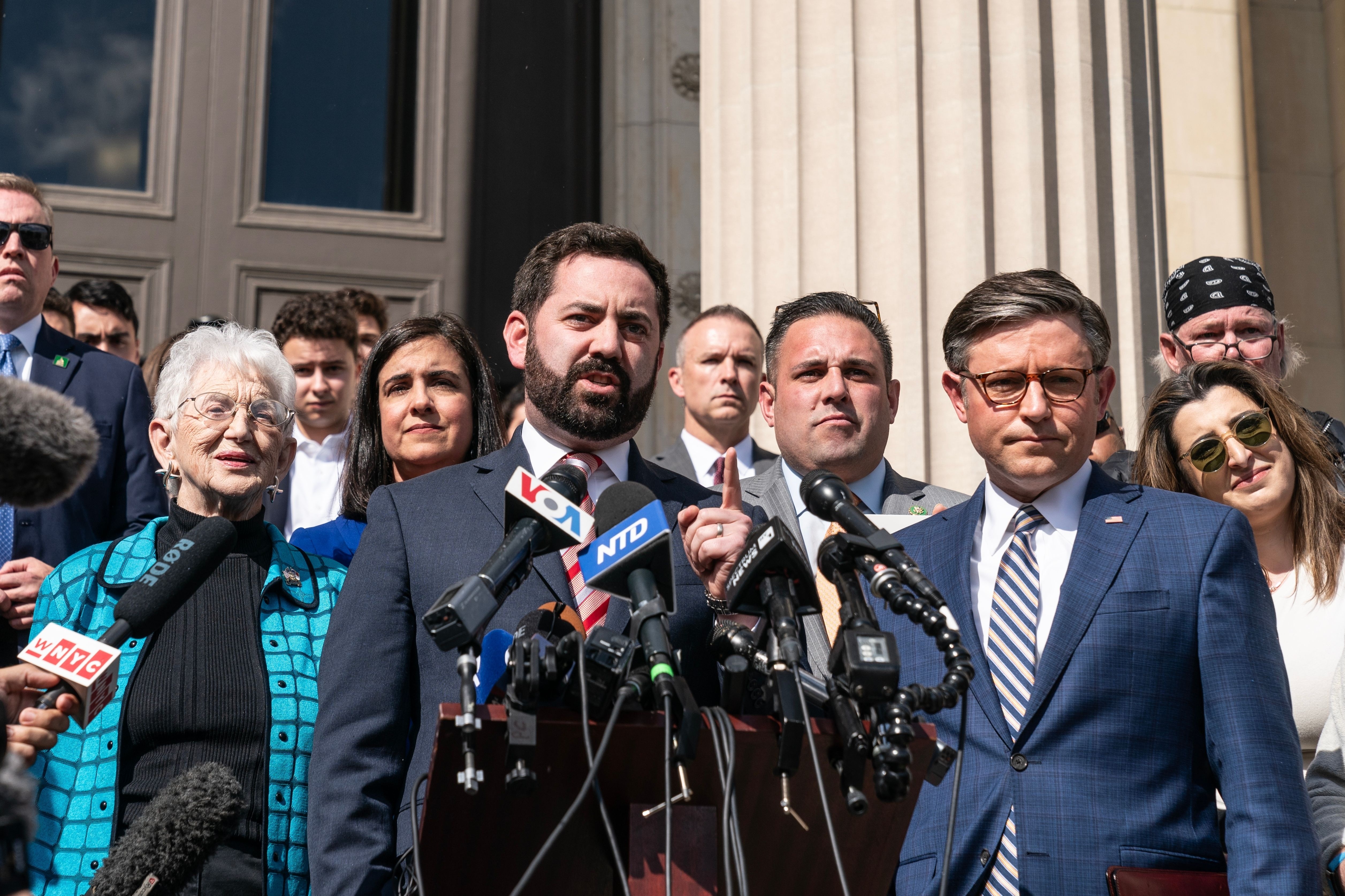Two men stand in front of a podium and microphones