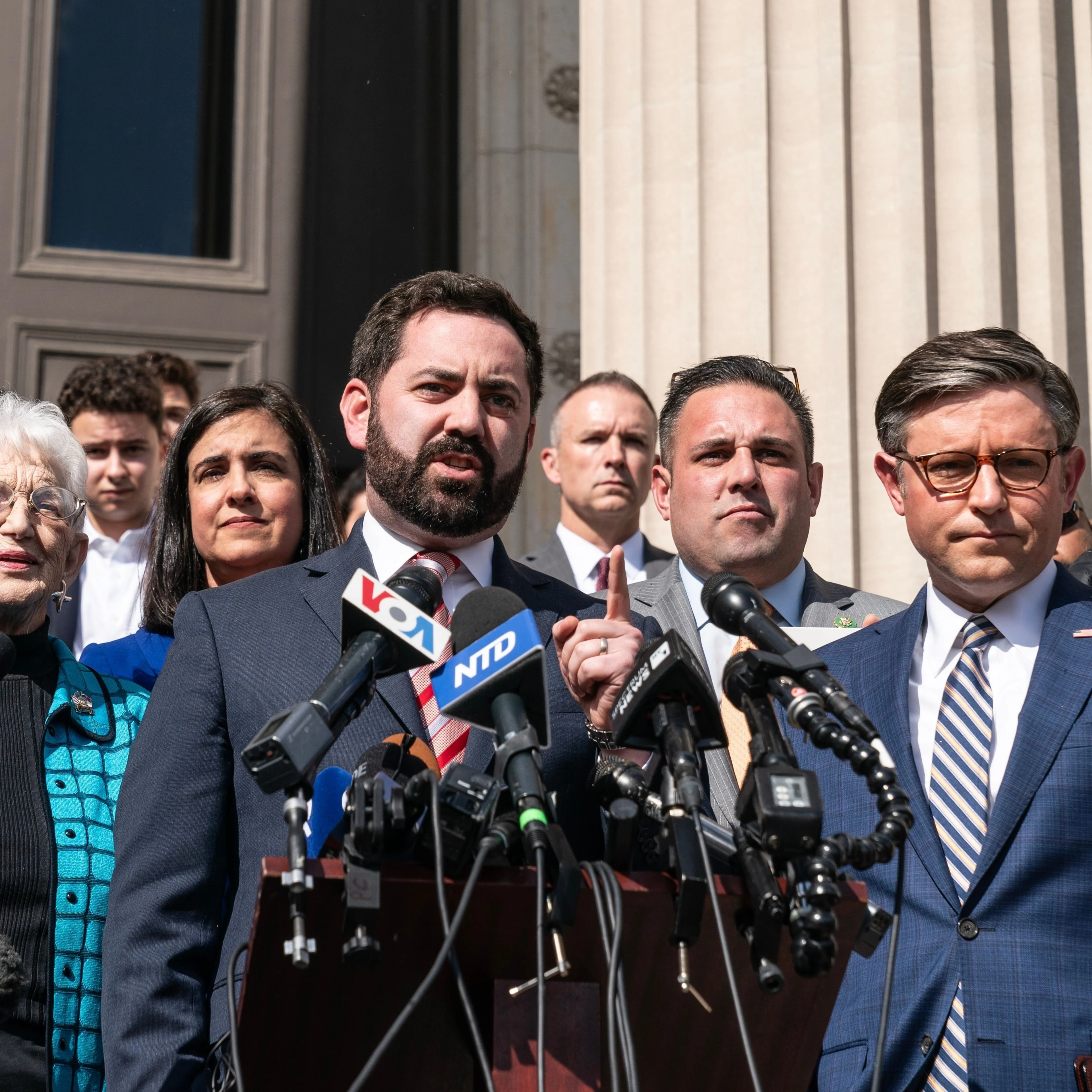 Two men stand in front of a podium and microphones