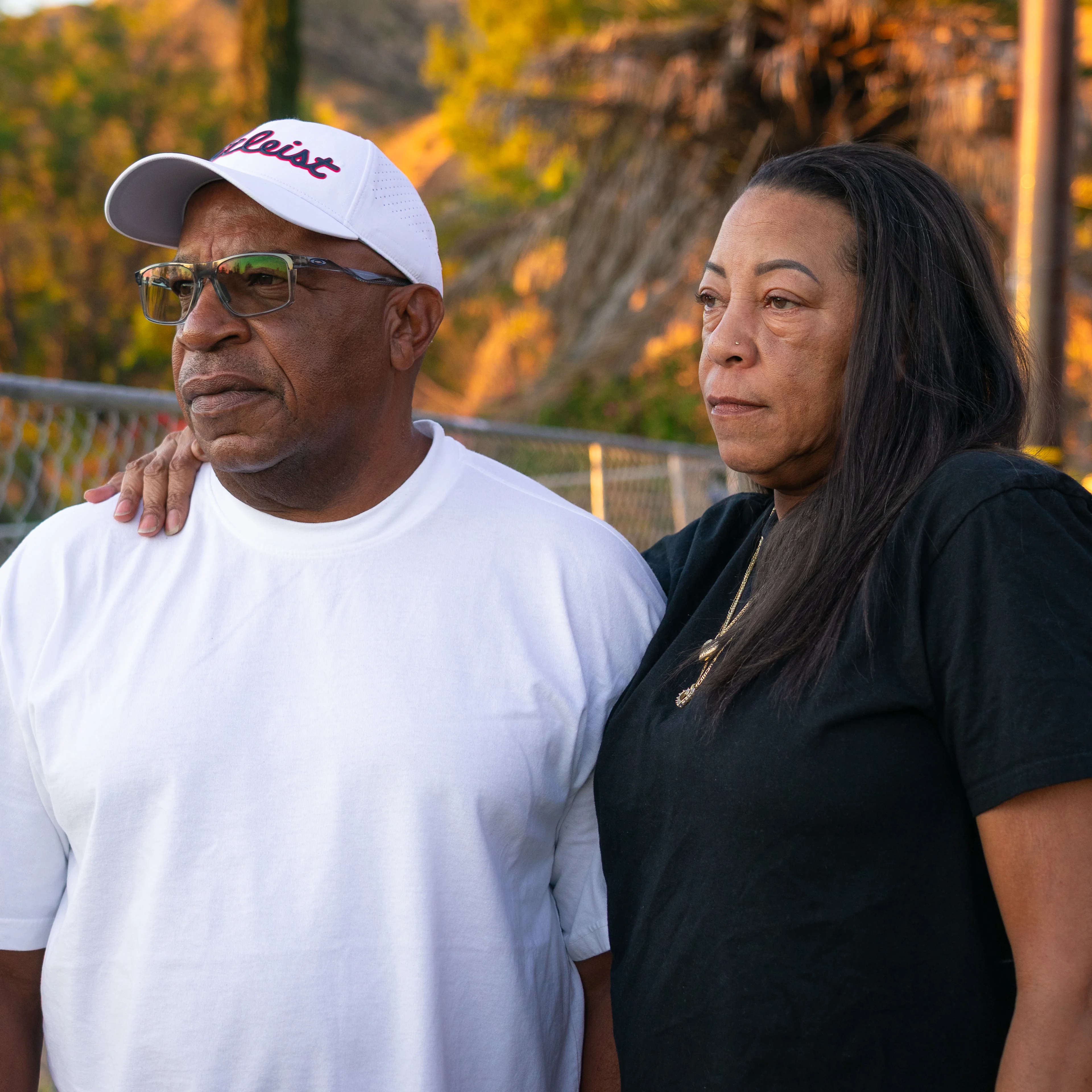 A close up profile photo of a woman with one arm around a mans shoulders.