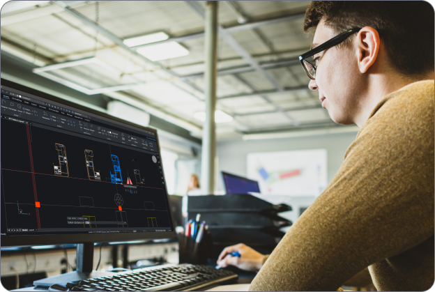 CAD DWG software - Main visual A man wearing glasses works at a desk, viewing a BricsCAD CAD interface displaying 2D floor plan drawings on a monitor.