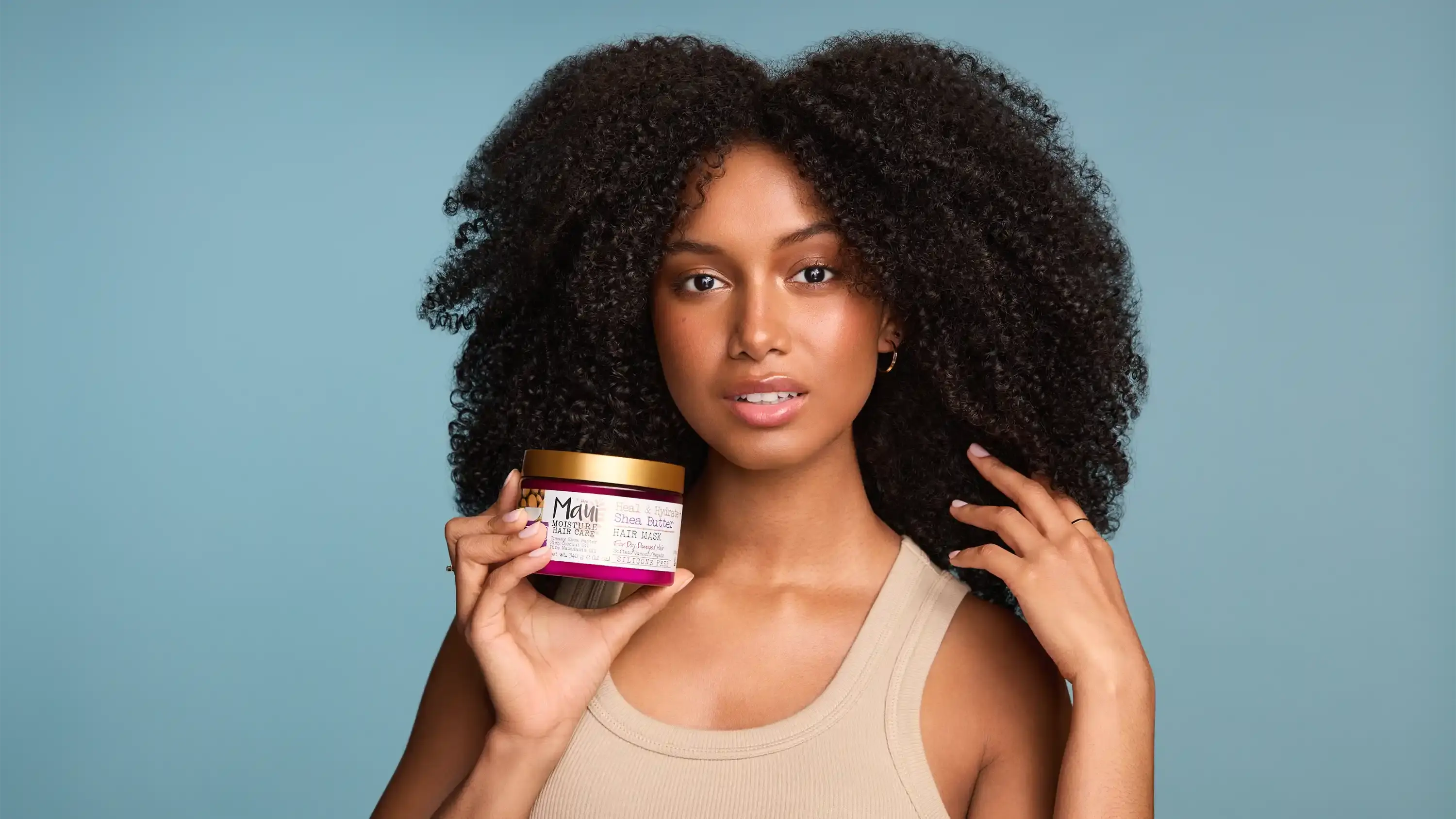 Woman with healthy curls holding Maul Moisture Heal & Hydrate + Shea Butter Hair Mask