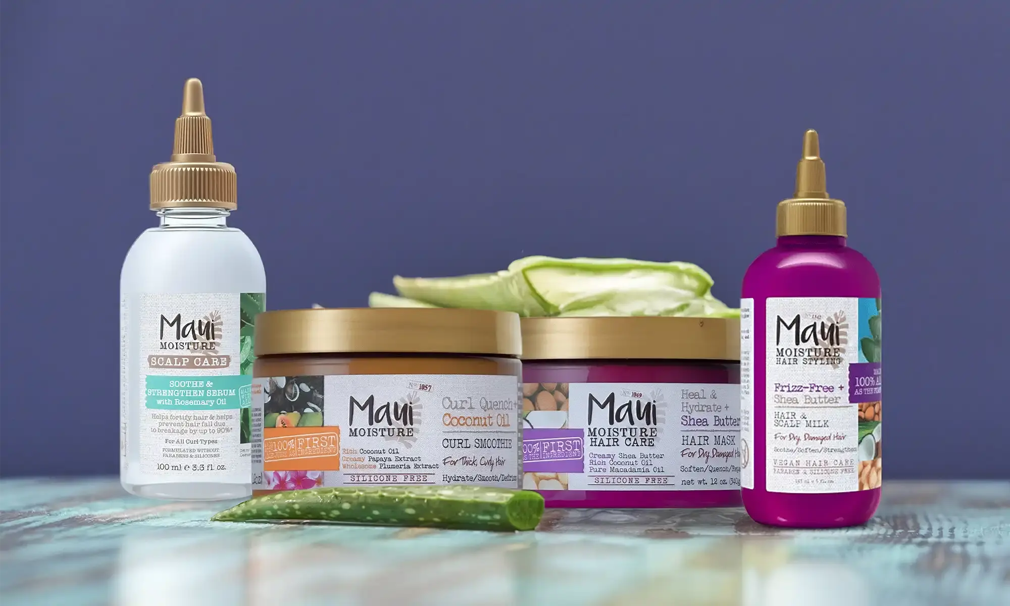 A jar of Maui Moisture® Curl Quench+ Coconut Oil Ultra-Hold Gel next to aloe leaves