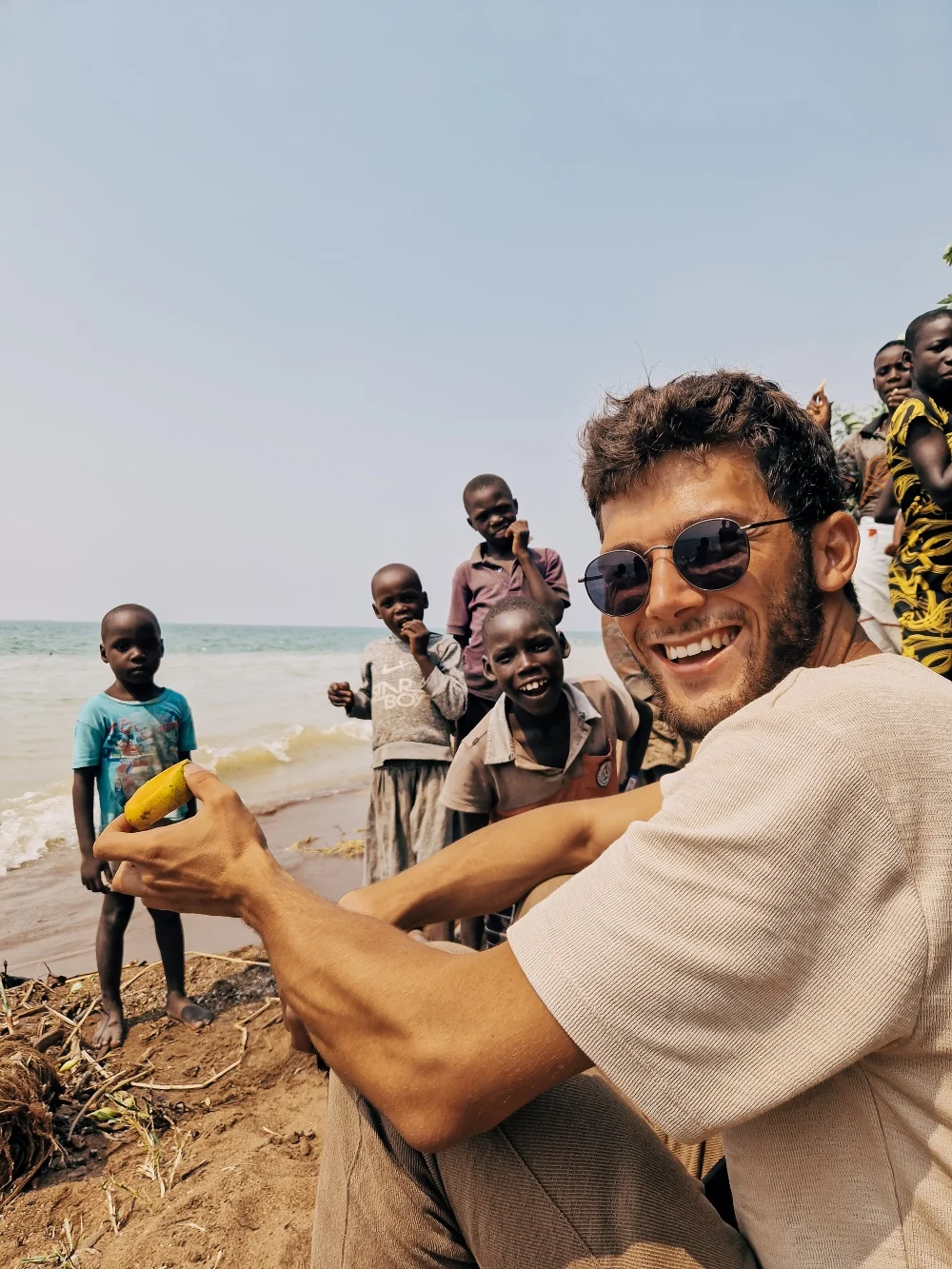 Pol with local kids, eating a mango on the shore of Lake Albert