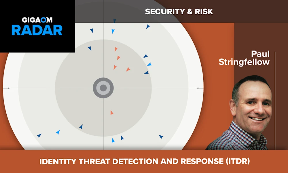 The image is titled "GIGAOM RADAR" and focuses on the topic of "SECURITY & RISK". It shows a radar chart with various triangular symbols scattered around the center, likely indicating different security threats or risks.
In the bottom right corner, there is a headshot of a smiling man with short dark hair wearing a blue and white checkered shirt. His name is listed as "Paul Stringfellow".
The bottom section has the text "IDENTITY THREAT DETECTION AND RESPONSE (ITDR)" in all capital letters, suggesting this radar chart is specifically related to assessing and responding to identity-based security threats within an organization's IT systems.
The color scheme features shades of orange and gray, giving it a serious and professional look fitting for a security and risk-focused infographic. Overall, the radar visualization aims to provide a high-level overview of the current state of identity threat detection capabilities.