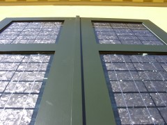 Solarer Fensterladen mit grünem Holzrahmen und silberfarbenen multikristallinen Solarzellen