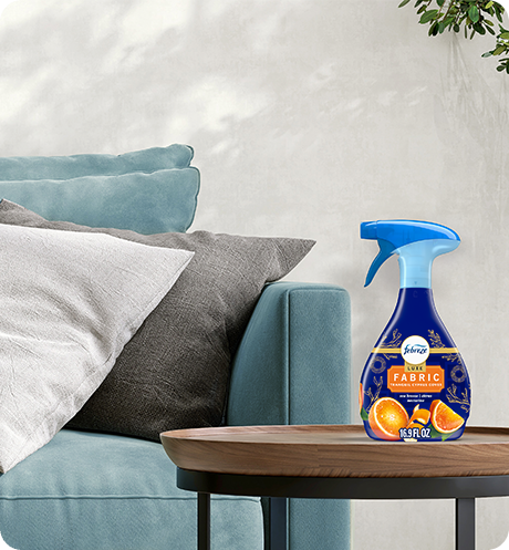 Febreze FABRIC Tranquil Cyprus Coves bottle sitting on a living room side table.