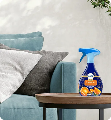 Febreze FABRIC Tranquil Cyprus Coves bottle sitting on a living room side table.