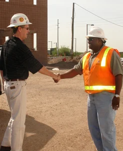 Two men shaking hands at a construction site