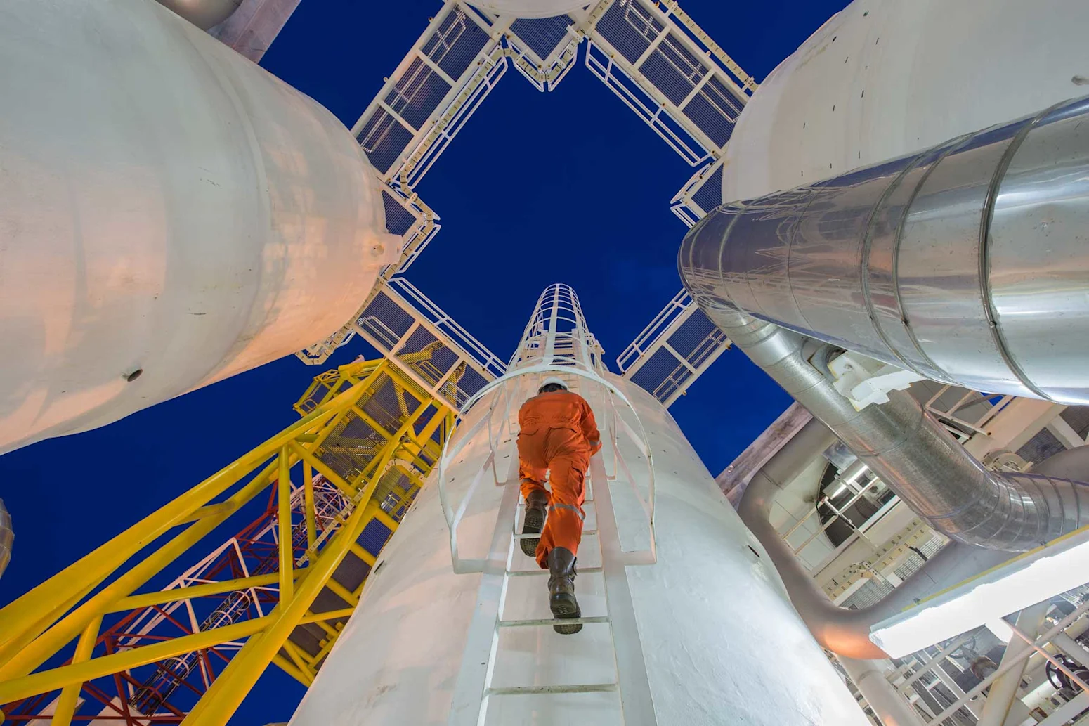 A Sunstate employee climbing a ladder at an industrial site