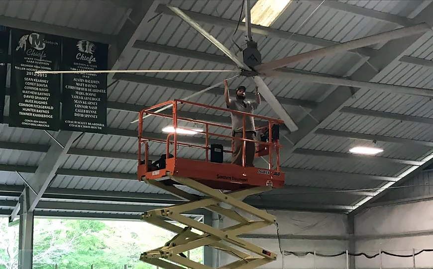 Installer working on a large electrical ceiling fan from a Sunstate Equipment scissor lift