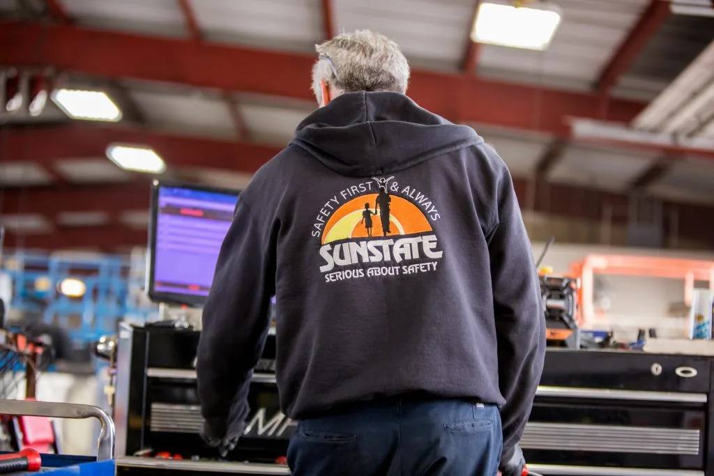 Person standing at computer with their back facing you wearing a hoodie that references safety