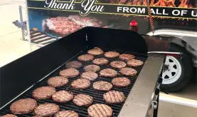 Burgers cooking on a large open outdoor gril