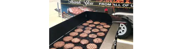 Burgers cooking on a large open outdoor gril