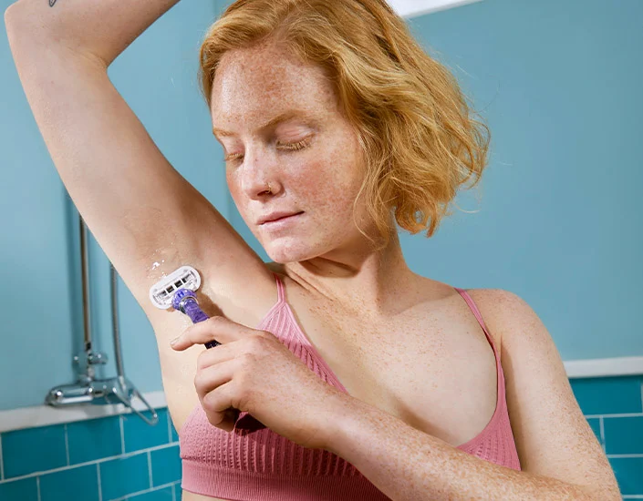 Mulher raspando os pelos das axilas