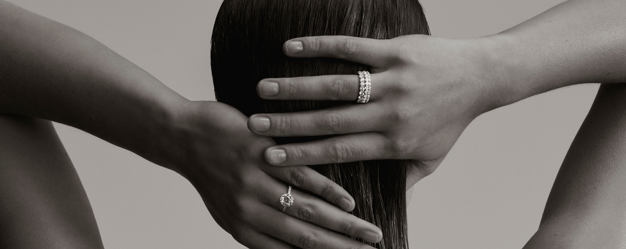 image taken from behind of a woman holding hear hair, wearing diamond rings