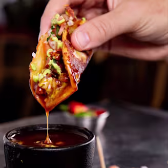 A hand dipping a Quorn Taco into a sauce