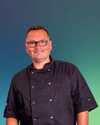 Paul Jennings headshot, Paul in black chefs jacket wearing glasses and smiling.
