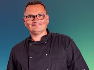Paul Jennings headshot, Paul in black chefs jacket wearing glasses and smiling.
