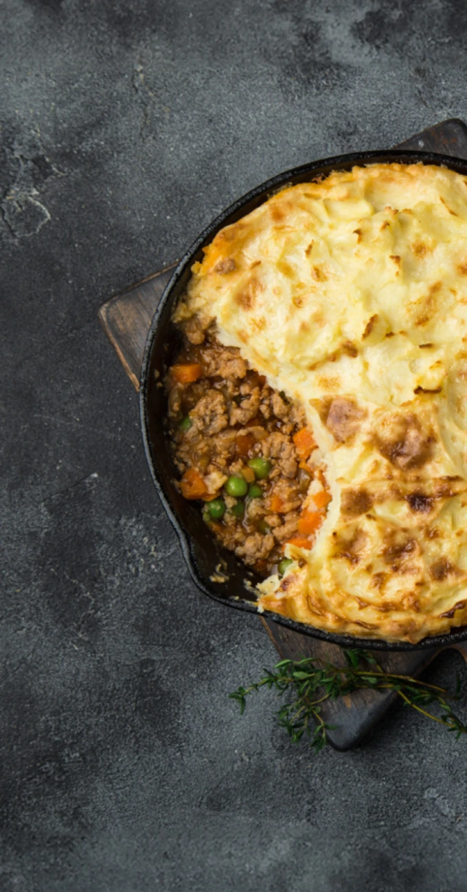 A cottage pie with some of the potato topping removed to show the Quorn inside