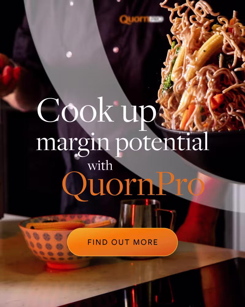 Food in a saucepan being tossed into the air in a kitchen with an orange basket on the side