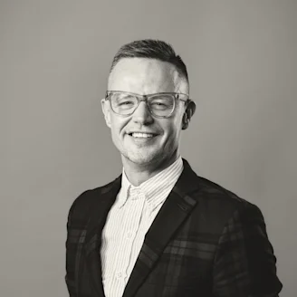Headshot of Dr Vincent Walsh, black and white, man with glasses and tartan suit