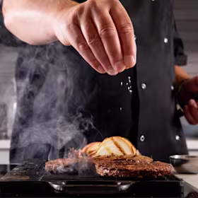 A hand sprinkling salt onto food