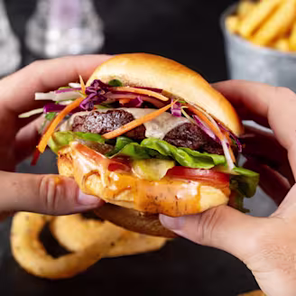 Hands holding a Quorn burger with sauce