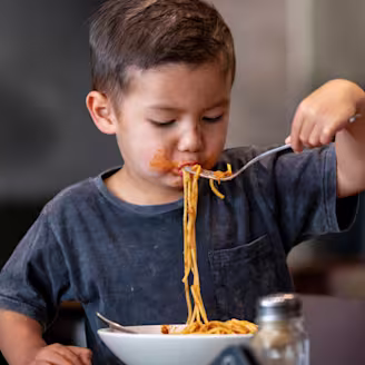Boy eating spaghetti bolognese out of a bowl