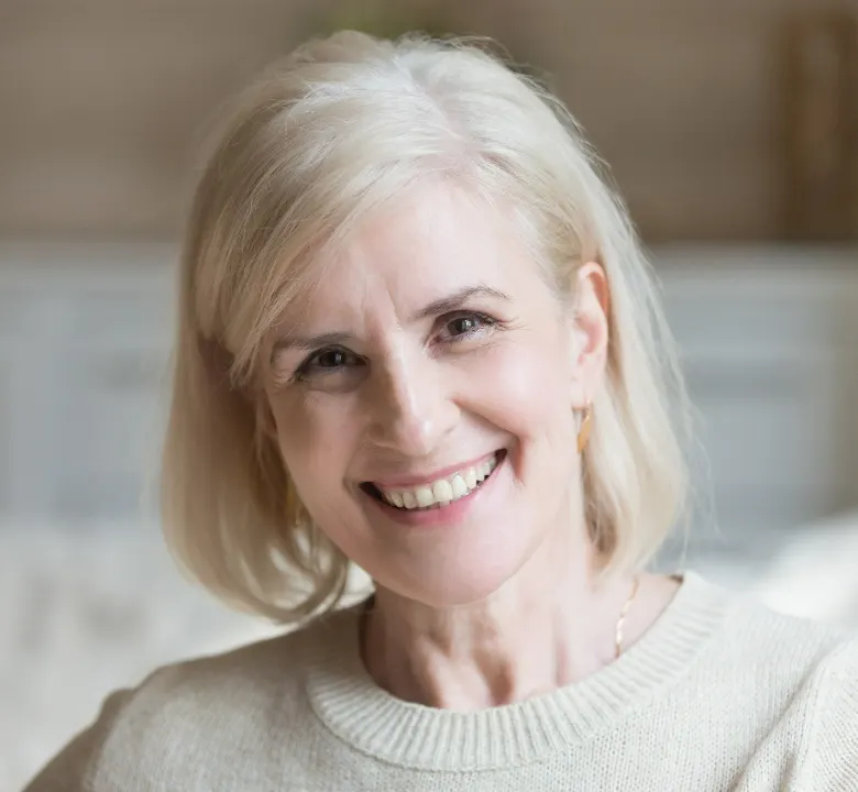 Happy smiling elderly grey thin haired woman looking at camera posing at home indoors.