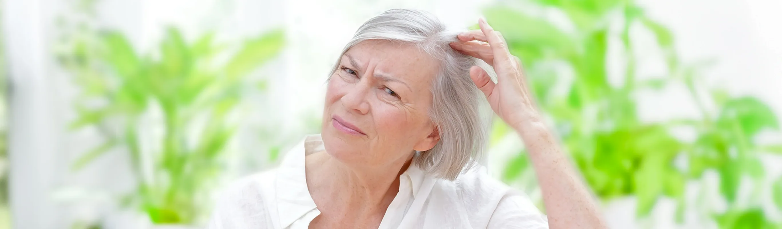 Anxious senior woman showing her scalp through thinning grey hair