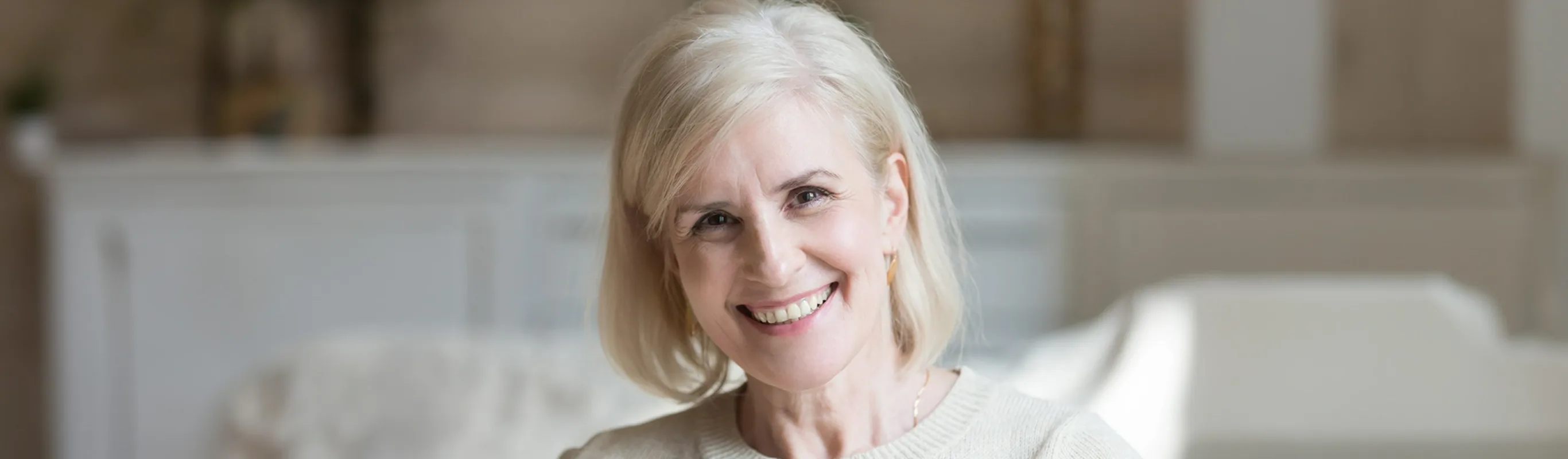 Happy smiling elderly grey thin haired woman looking at camera posing at home indoors.