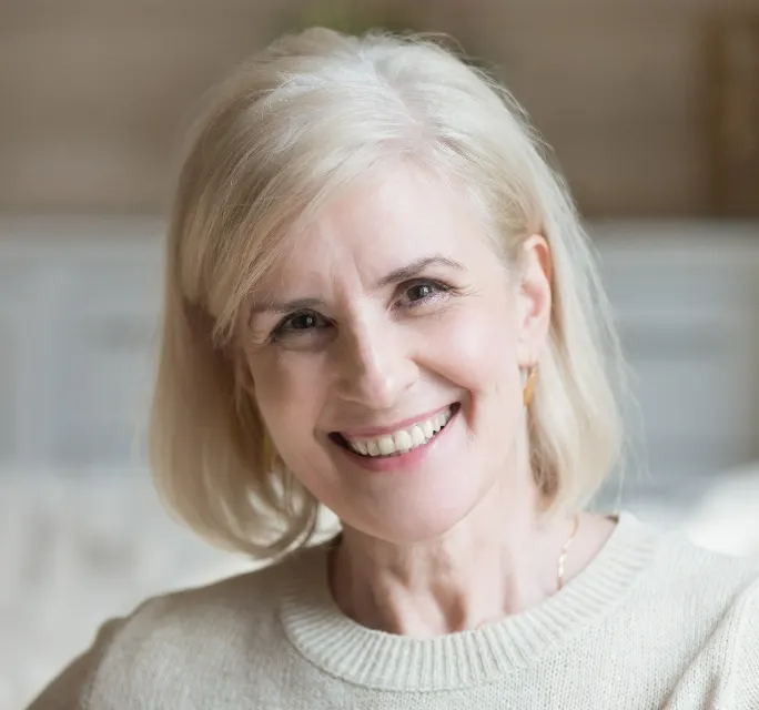 Happy smiling elderly grey thin haired woman looking at camera posing at home indoors.