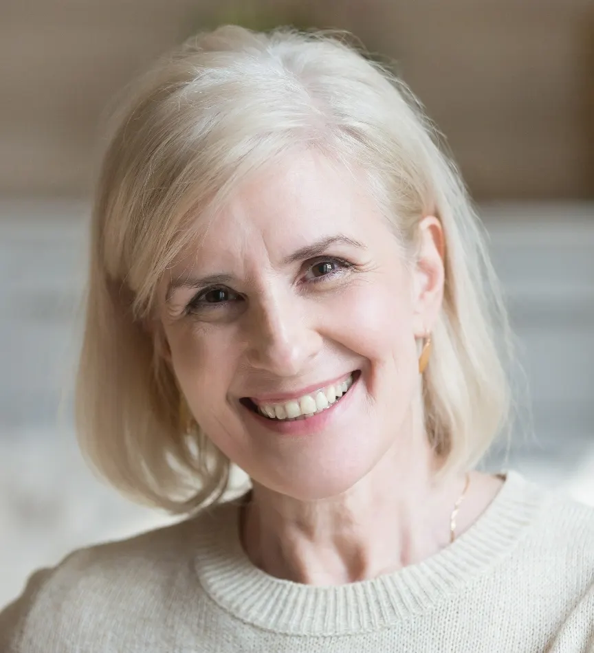 Happy smiling elderly grey thin haired woman looking at camera posing at home indoors.