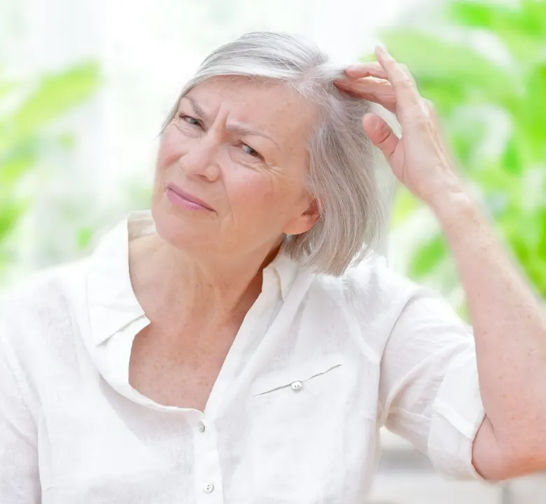 Anxious senior woman showing her scalp through thinning grey hair