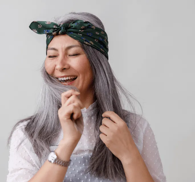 A women in white embracing her silver shiny hair