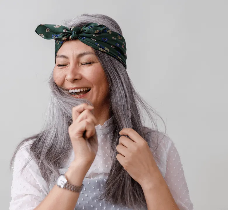 A women in white embracing her silver shiny hair