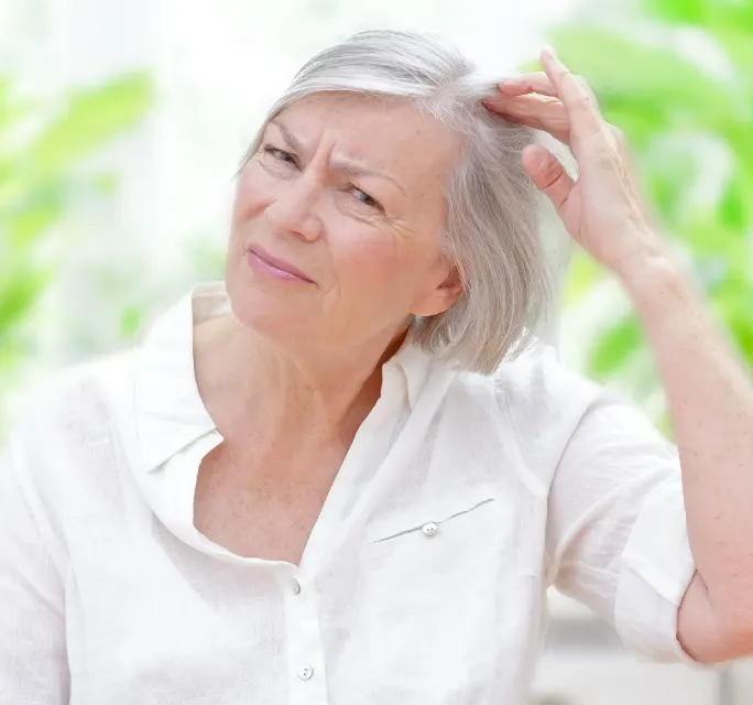 Anxious senior woman showing her scalp through thinning grey hair