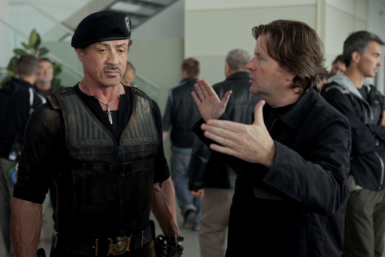 a man in a black hat talking to a man in a black suit